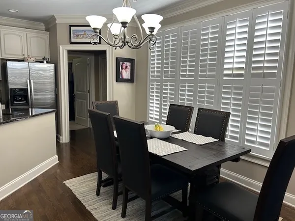 a living room with stainless steel appliances a dining table wooden floor and a window