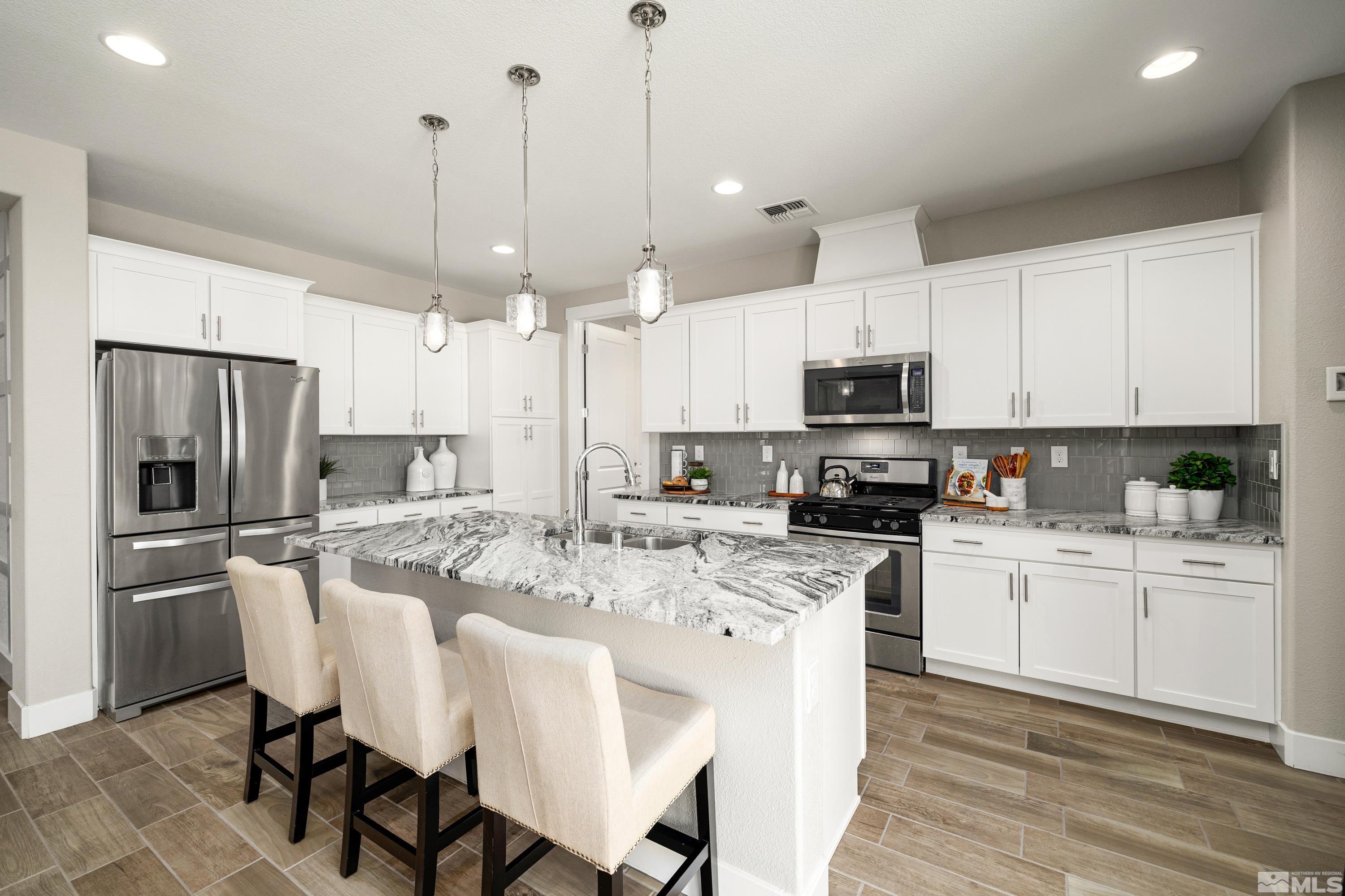 9940 Bernborough Drive Reno, NV 89521 - Photo 5 of 40 a large kitchen with white cabinets stainless steel appliances and a center island