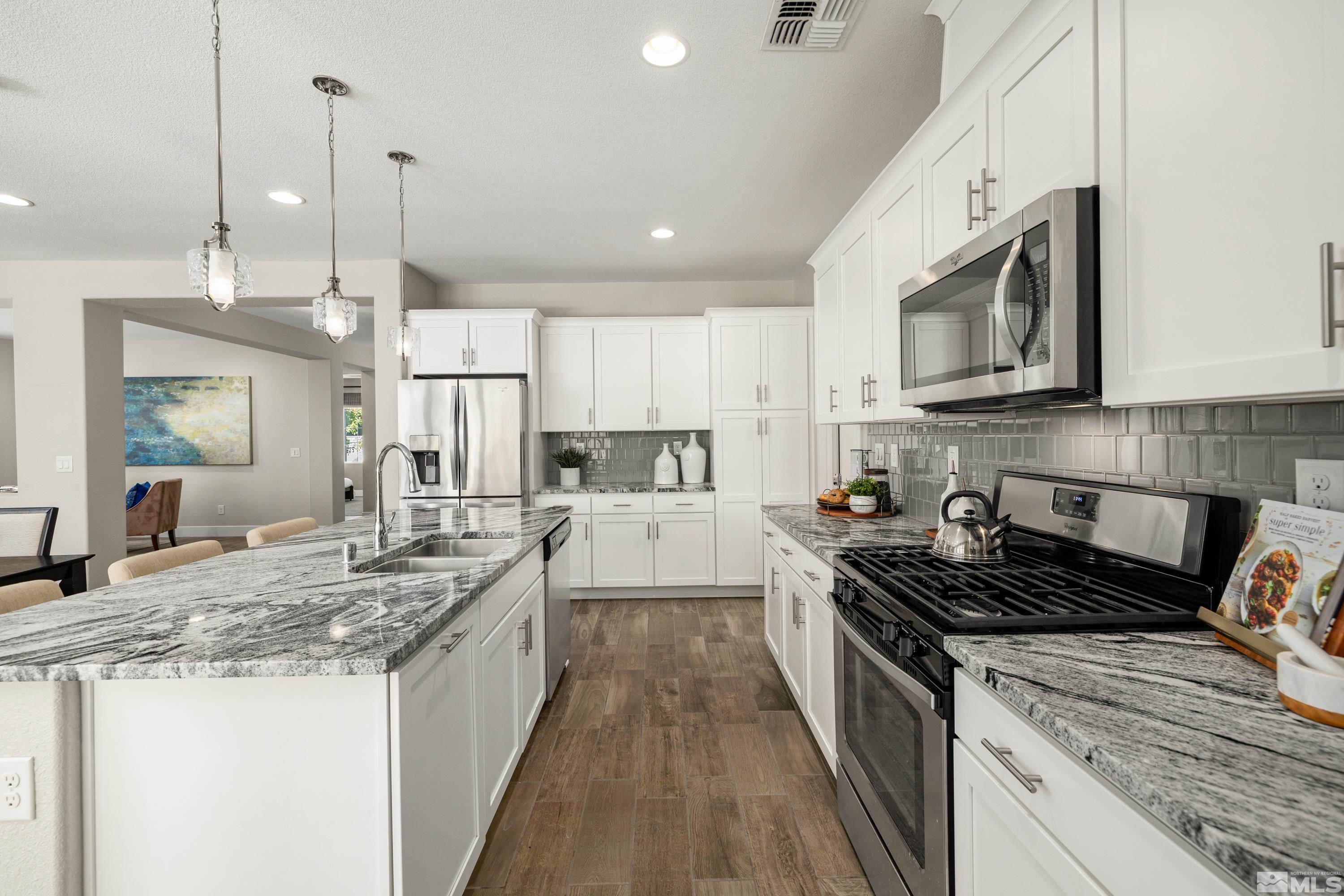 9940 Bernborough Drive Reno, NV 89521 - Photo 6 of 40 a kitchen with stainless steel appliances granite countertop a stove a sink and a microwave