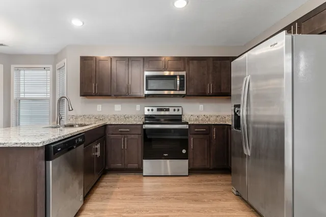 a kitchen with granite countertop a refrigerator and a stove top oven