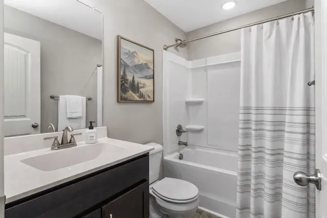 a bathroom with a sink a toilet a mirror a vanity and shower