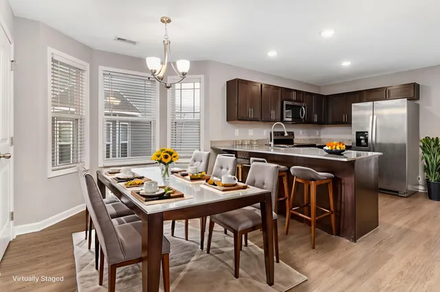 a kitchen with stainless steel appliances granite countertop a stove a refrigerator a sink a stove a dining table and chairs