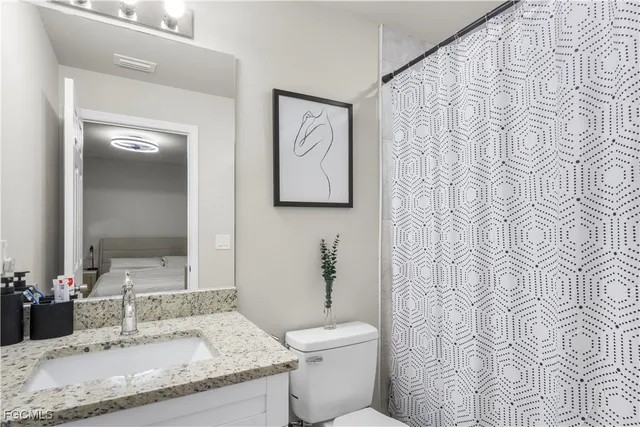 a bathroom with a granite countertop sink a toilet and a mirror