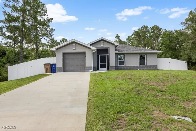 a front view of house with yard and trees in the background