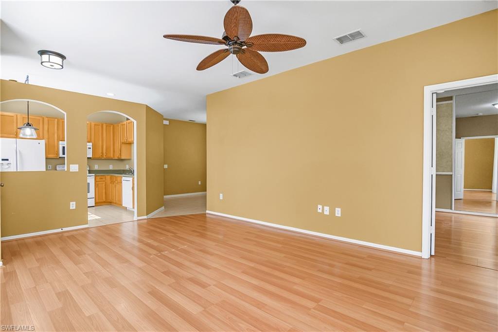 7820 Sandpine Court, Unit 2304 Naples, FL 34104 - Photo 11 of 50 a view of an empty room with wooden floor and a ceiling fan