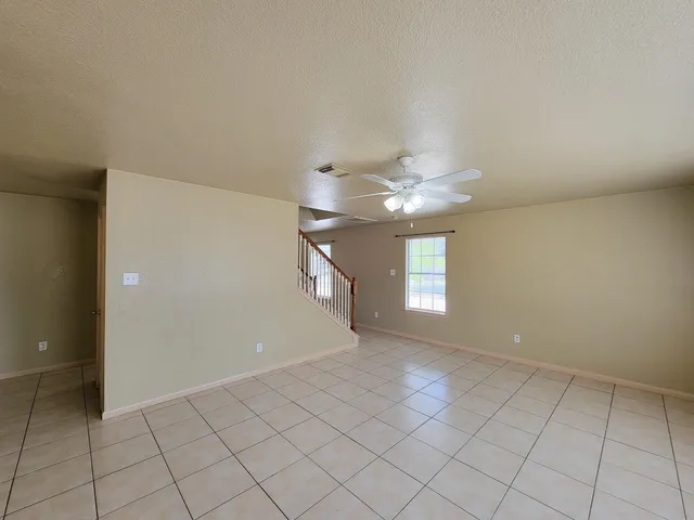 a view of an empty room with window and chandelier fan