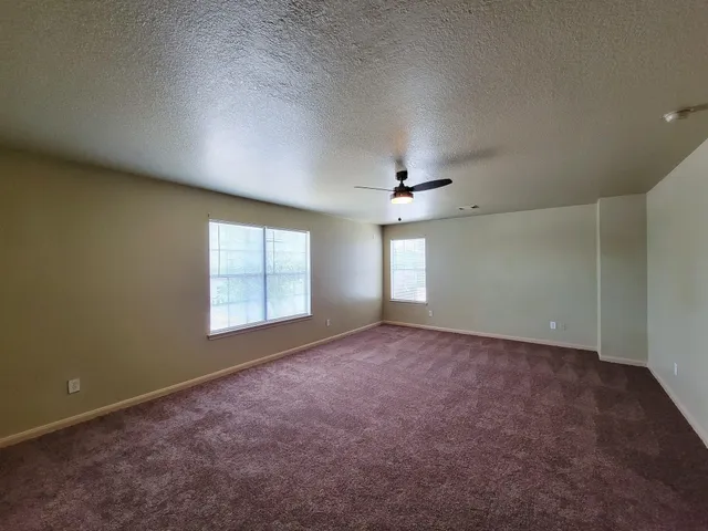 an empty room with windows and fan
