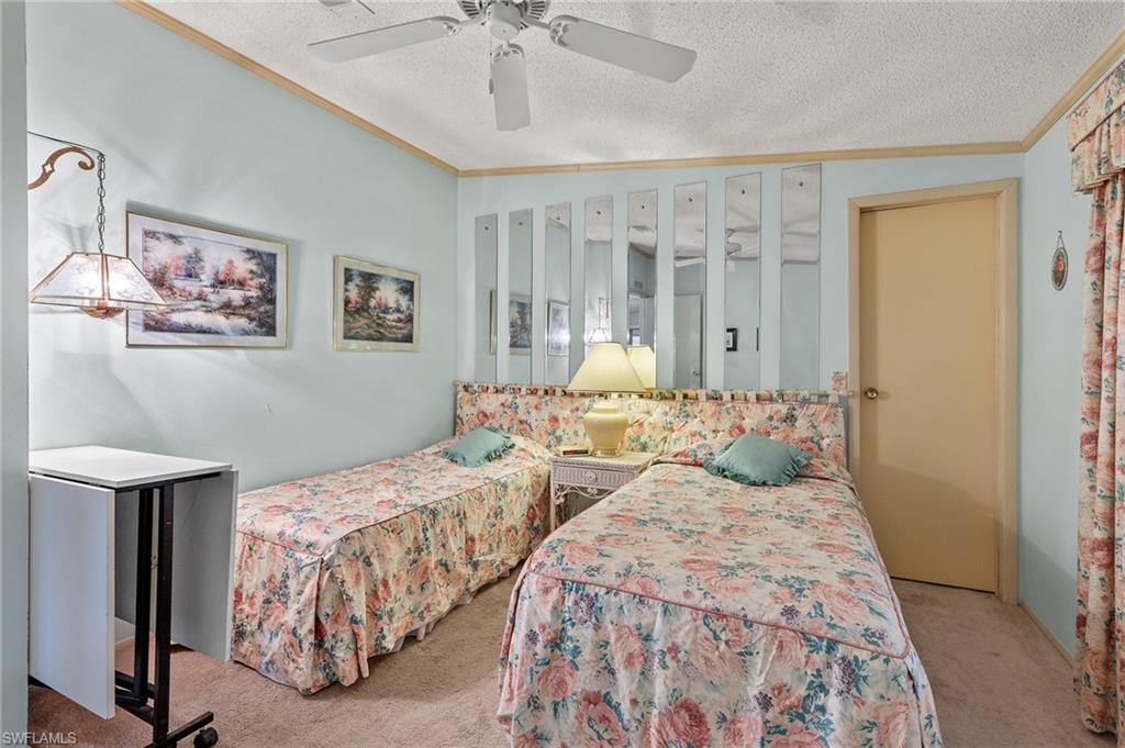 48 Oceans Boulevard, Unit 48 Naples, FL 34104 - Photo 19 of 26 a bedroom with two beds and a chandelier