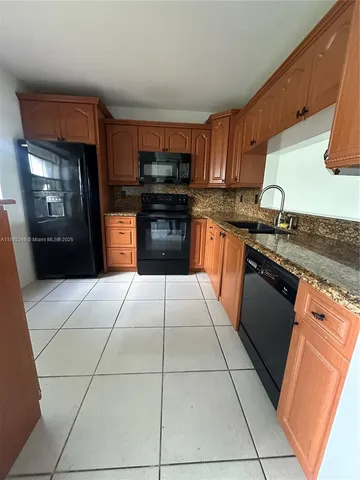 a kitchen with granite countertop a stove a sink and a refrigerator