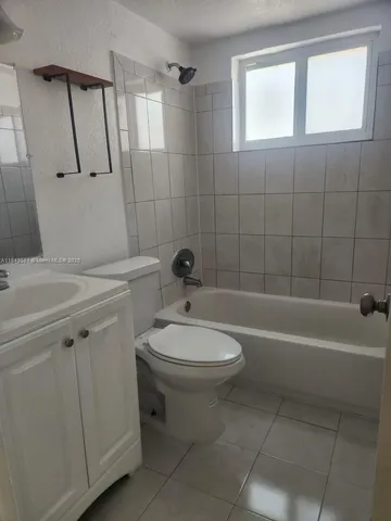 a bathroom with a toilet a sink a mirror and bathtub
