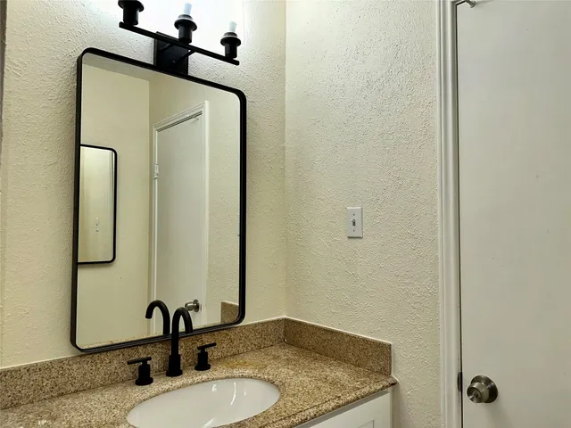 a bathroom with a granite countertop sink and a mirror