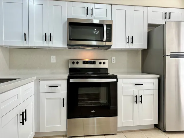 a kitchen with stainless steel appliances granite countertop white cabinets and a stove
