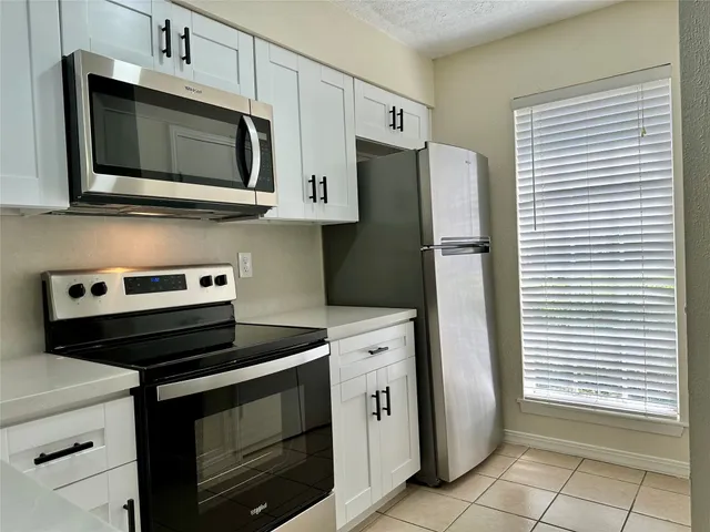 a kitchen with stainless steel appliances white cabinets and a stove top oven