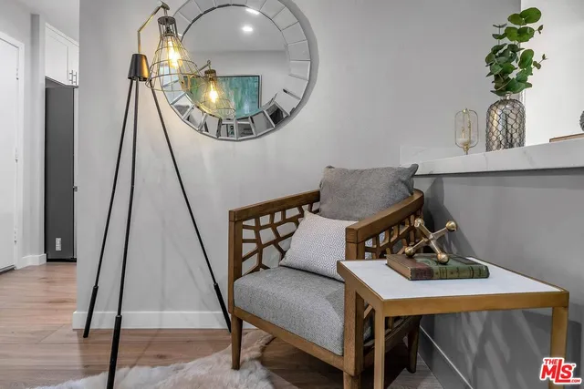 a living room with a mirror furniture and a wooden floor