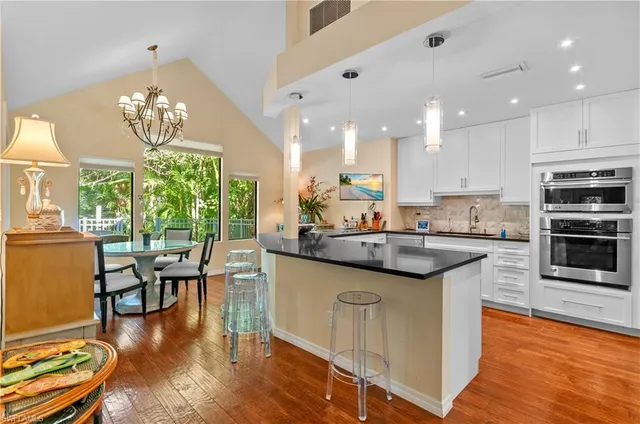 a kitchen with stainless steel appliances granite countertop a stove top oven a sink dishwasher a dining table and chairs with wooden floor