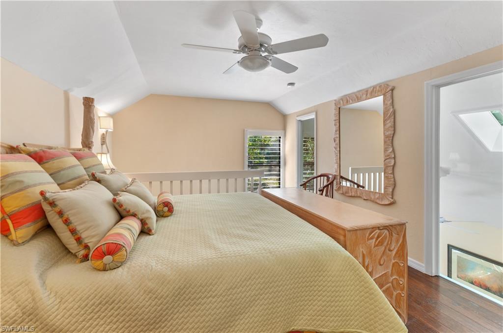 1313 Solana Road, Unit A3 Naples, FL 34103 - Photo 21 of 29 Bedroom with vaulted ceiling, a ceiling fan, and wood finished floors loft above living room stairs