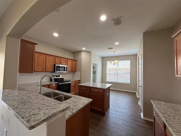 a kitchen with stainless steel appliances granite countertop sink stove refrigerator and wooden floor