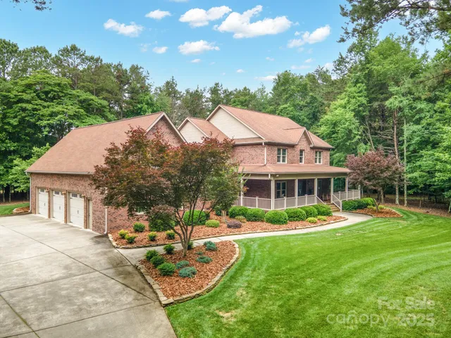 a front view of a house with garden and trees