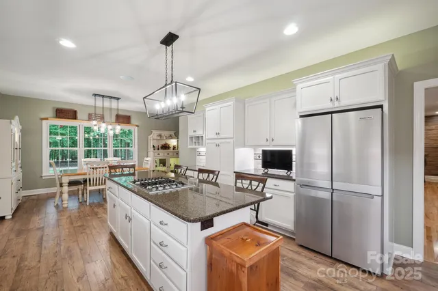 a kitchen that has a lot of cabinets stainless steel appliances and a large window