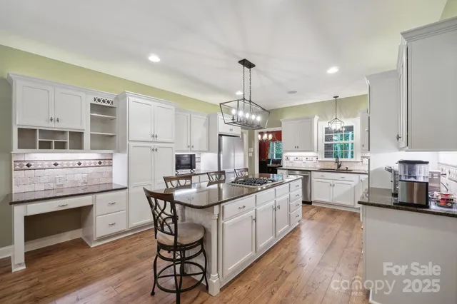a kitchen with stainless steel appliances a white wooden cabinets and stove top oven