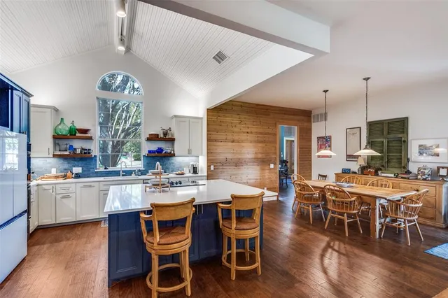 a dining room with stainless steel appliances kitchen island granite countertop a table chairs and a refrigerator