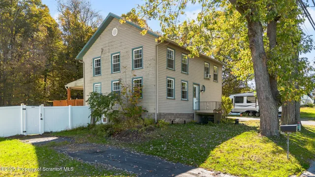 a view of a white house with a big yard and potted plants