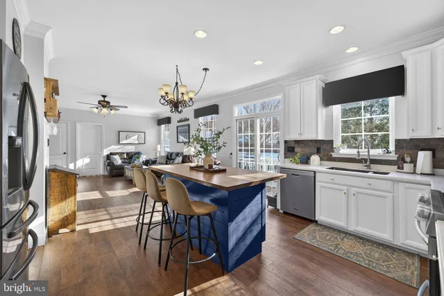 a kitchen with stainless steel appliances granite countertop a refrigerator a stove a sink dishwasher and a dining table with the living room view