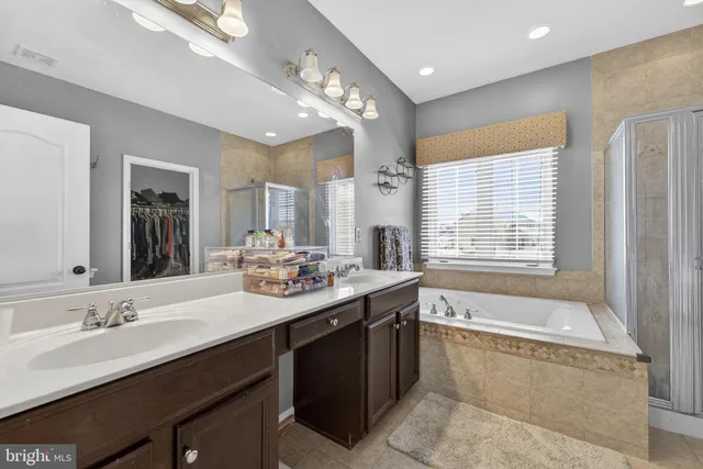 a bathroom with a tub sink double vanity granite and a shower