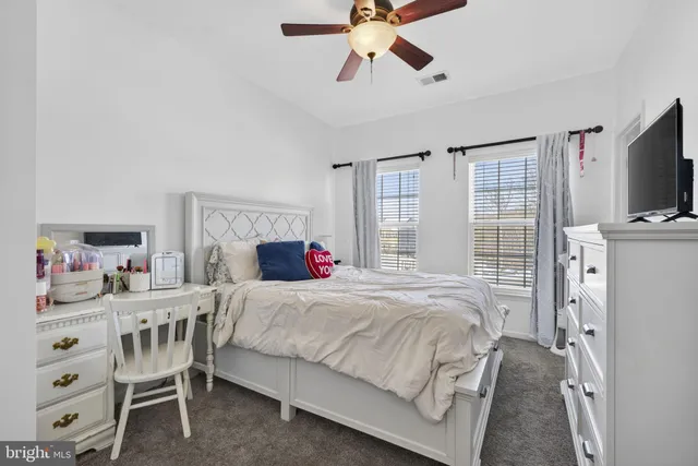 a bedroom with a bed a chandelier and dresser
