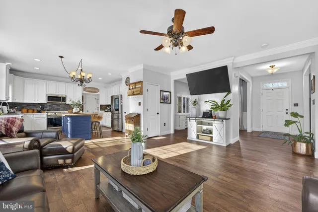 a living room with furniture kitchen view and a wooden floor