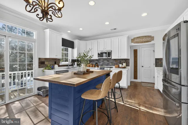 a kitchen with stainless steel appliances granite countertop a sink a stove a refrigerator cabinets and dining table