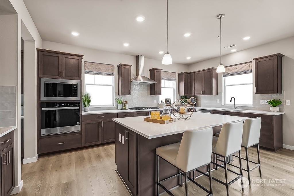 16213 Southeast 133rd Place, Unit 113 Renton, WA 98059 - Photo 11 of 30 a kitchen with stainless steel appliances granite countertop a stove a sink a kitchen island a stove and a refrigerator with wooden floor