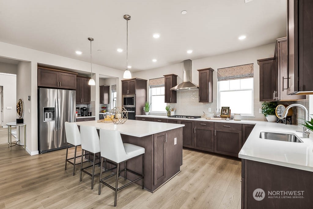 16213 Southeast 133rd Place, Unit 113 Renton, WA 98059 - Photo 12 of 30 a kitchen with stainless steel appliances granite countertop a sink a stove a refrigerator cabinets and wooden floor
