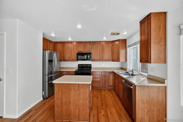 a kitchen with stainless steel appliances granite countertop sink stove refrigerator and cabinets