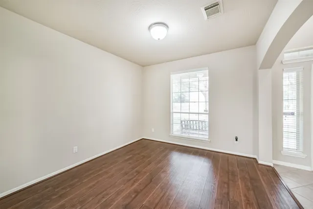 an empty room with wooden floor and windows