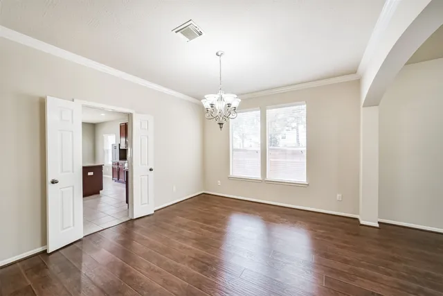 a view of a room with wooden floor chandelier and windows