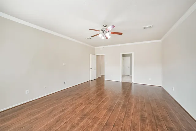 a view of empty room with wooden floor and fan