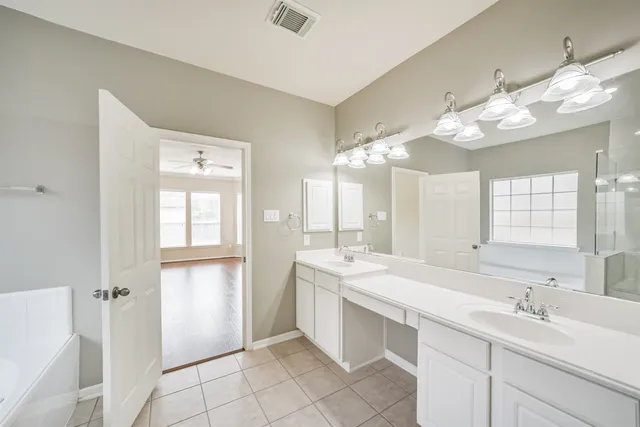 a spacious bathroom with a double vanity sink mirror and a bathtub