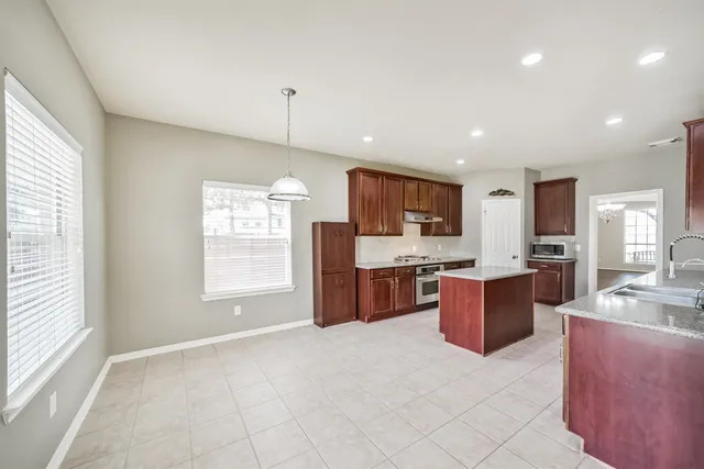 a large white kitchen with a large window in it and stainless steel appliances