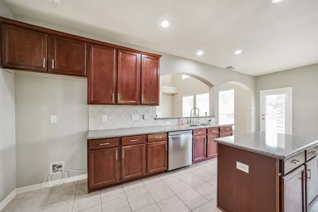 a large kitchen with stainless steel appliances granite countertop a sink counter space cabinets and a large window