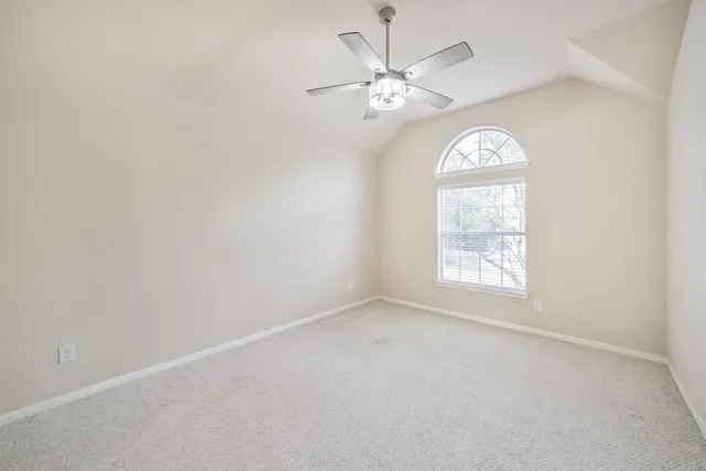 an empty room with a window and a chandelier fan