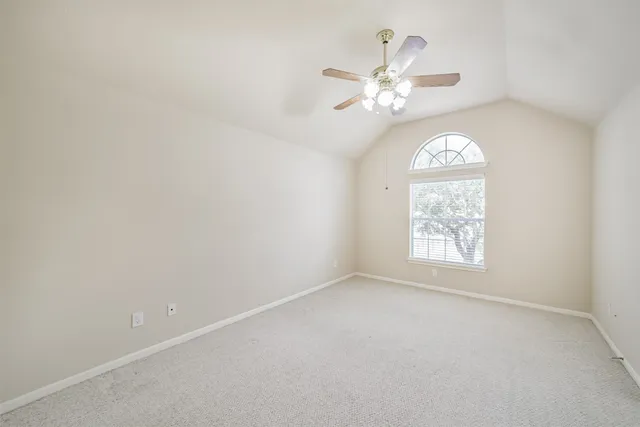 an empty room with a chandelier fan and windows