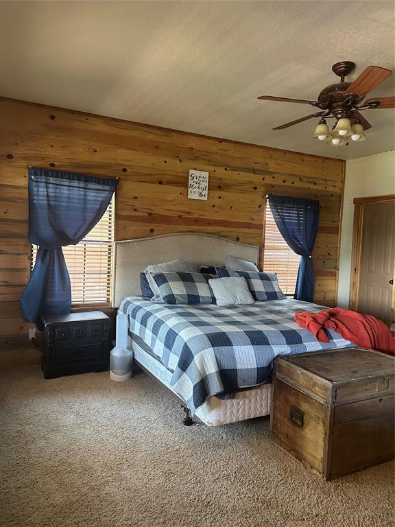 572 Oak Point Drive May, TX 76857 - Photo 24 of 36 Bedroom with carpet, wood walls, and ceiling fan