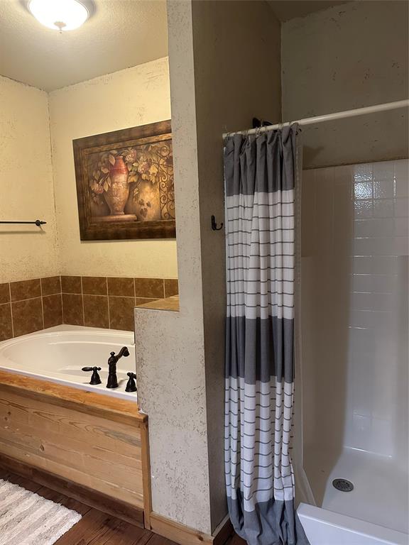 572 Oak Point Drive May, TX 76857 - Photo 25 of 36 Full bathroom featuring a bath, a shower stall, and wood finished floors