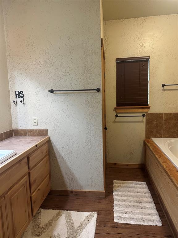 572 Oak Point Drive May, TX 76857 - Photo 28 of 36 Full bath featuring vanity, a bath, and wood finished floors