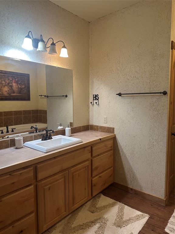 572 Oak Point Drive May, TX 76857 - Photo 29 of 36 Bathroom with wood finished floors, vanity, a textured wall, and a tub