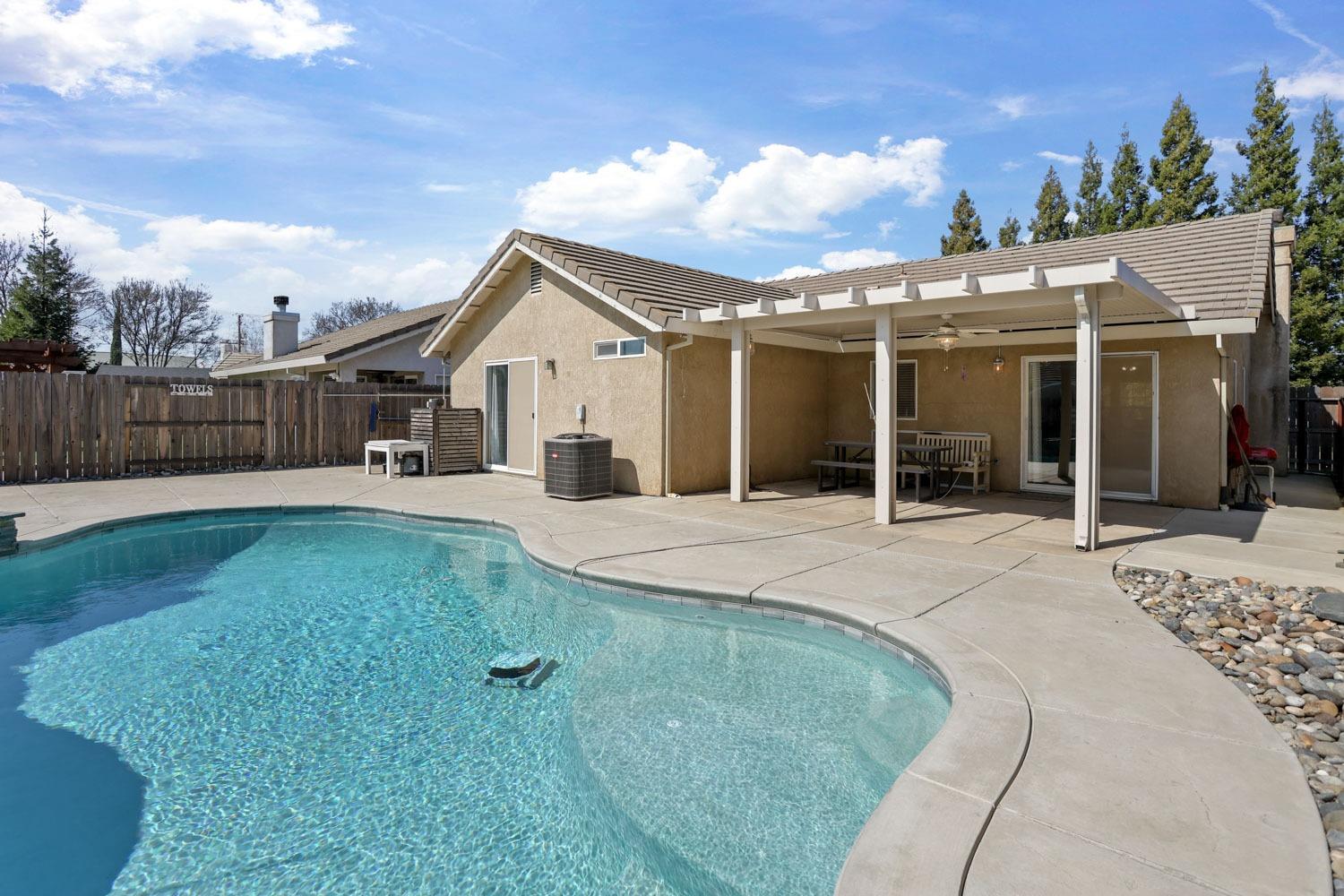 a view of a white house with a yard plants and large tree