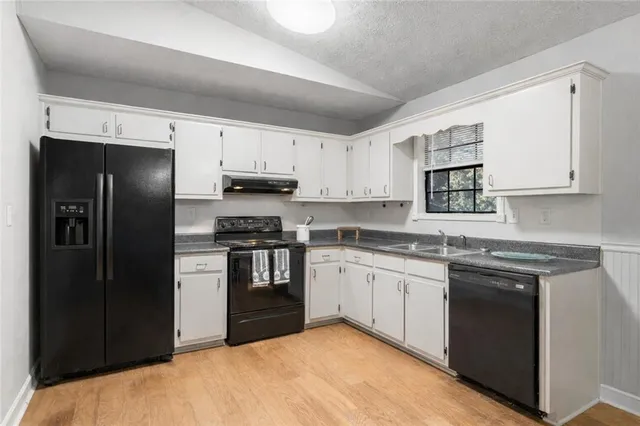 a kitchen with granite countertop white cabinets and stainless steel appliances