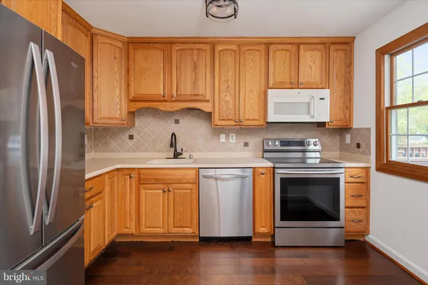a kitchen with stainless steel appliances a stove a sink and a refrigerator with wooden floor