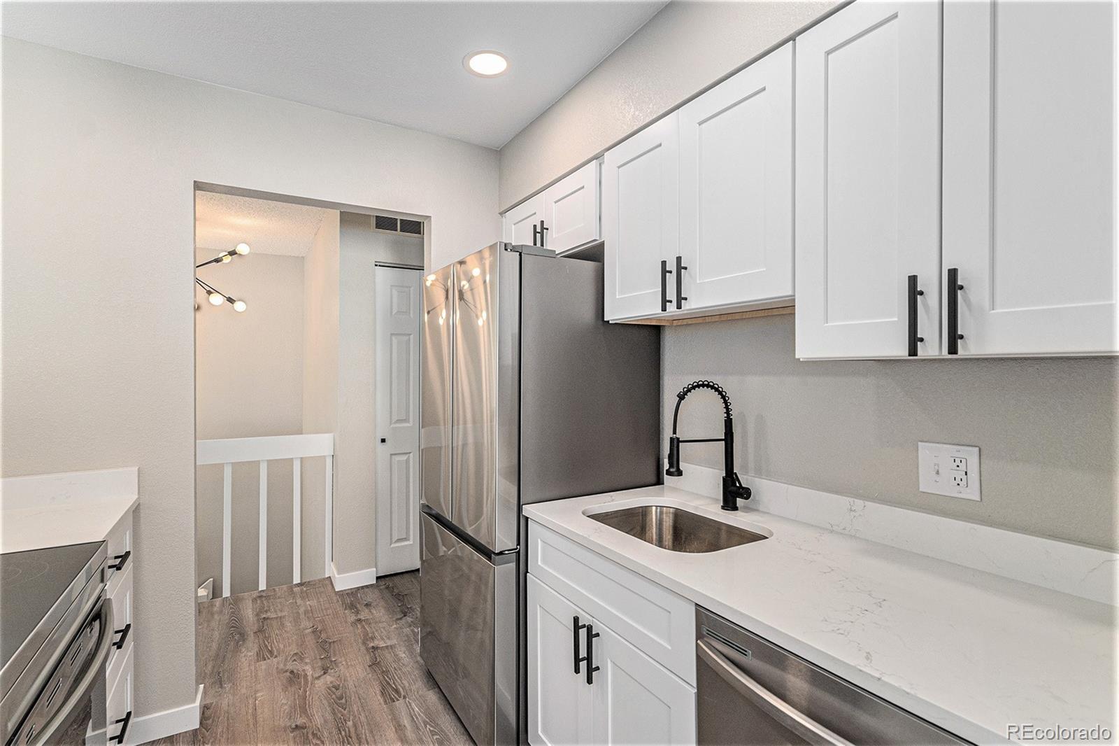 8414 South Everett Way, Unit F Littleton, CO 80128 - Photo 3 of 13 a kitchen with stainless steel appliances a sink a refrigerator and cabinets